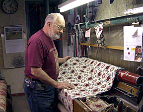 David Kiline checks a piece of fabric from one of his looms.